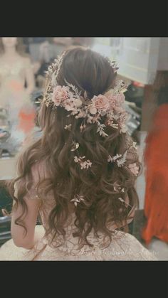 the back of a woman's head with long hair and flowers in her hair