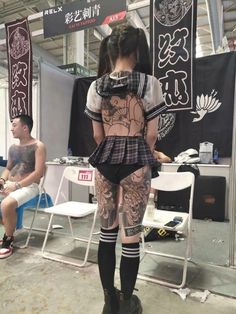 a woman with tattoos on her back standing next to a man