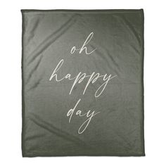 a blanket with the words oh happy day written in white ink on it, against a gray background