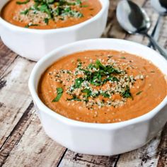 a white bowl filled with carrot soup on top of a wooden table