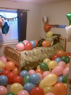 a room filled with lots of balloons and streamers in the air next to a bed