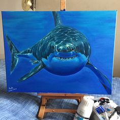 a painting of a great white shark on an easel next to some paint cans