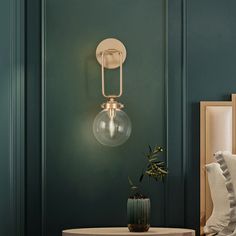 a bedroom with green walls and a round table in front of the wall light that has a clear glass ball on it