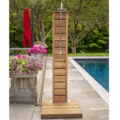 a tall wooden tower sitting next to a pool with flowers in the foreground and an umbrella hanging over it