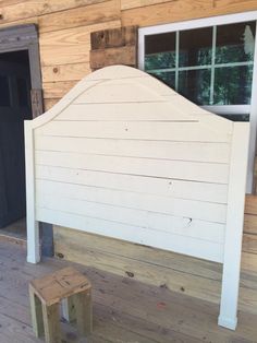 a little boy standing in the doorway of a wooden house with a white headboard