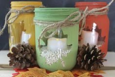 three mason jars decorated with pine cones, candles and some twine on the table