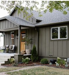 a gray house with white flowers in the front yard and steps leading up to it