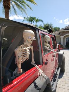 a skeleton sitting in the back of a red truck