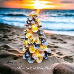 a christmas tree made out of seashells sitting on the sand at the beach