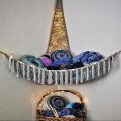 a basket filled with yarn sitting on top of a wall next to a string light