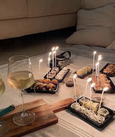 a table topped with trays of food and glasses of wine next to each other