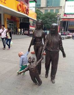 a little boy playing with a statue on the sidewalk