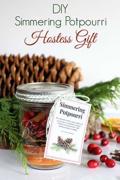 a glass jar filled with holiday gifts next to pine cones