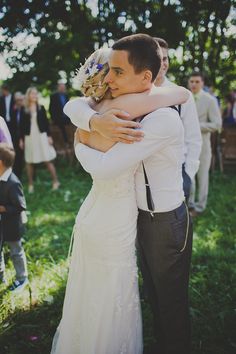 a bride and groom hugging each other in the grass