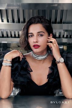 a woman sitting at a table with her hands on her head and wearing bracelets