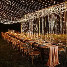 an outdoor dining area with string lights strung over the tables and chairs, along with candles