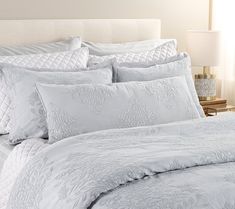 a bed with white comforter and pillows on it