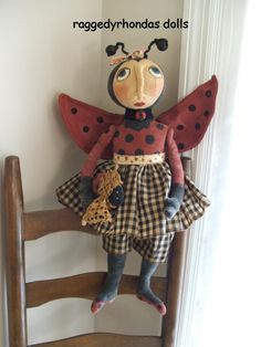 a lady bug doll sitting on top of a wooden chair next to a white wall