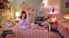 a woman sitting on top of a bed talking on a cell phone in a bedroom