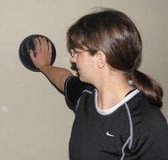 a woman holding a black object in her right hand and looking at the wall behind her