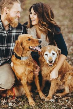 a man and woman sitting next to two dogs