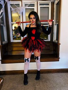 a woman dressed up as a devil holding a stick in front of an open window