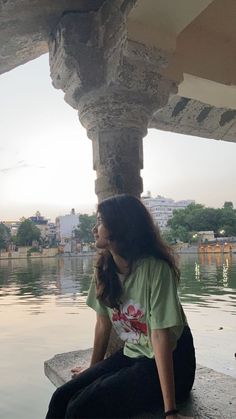 a woman sitting on the edge of a body of water