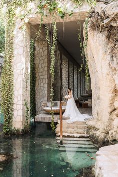 a woman in a wedding dress standing on some steps next to a body of water