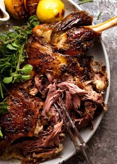 a white plate topped with meat and veggies next to lemons on a table