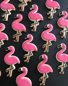 decorated cookies in the shape of pink flamingos on a black table with white icing