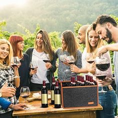 a group of people standing around a table with wine glasses and bottles in front of them