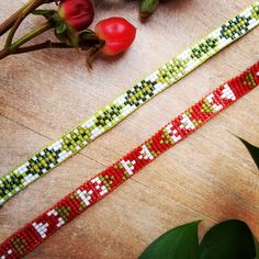 two colorful bracelets sitting on top of a wooden table next to flowers and leaves