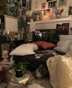 an unmade bed in a messy room with many pictures on the wall above it