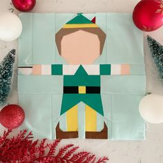 an ornament made to look like a paper cut out of a person wearing a green and yellow outfit