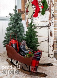 a sleigh with christmas stockings and boots in it next to a small tree