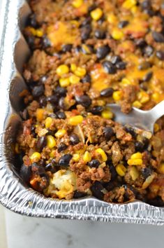 a casserole dish with corn, black beans and ground beef is shown in a pan