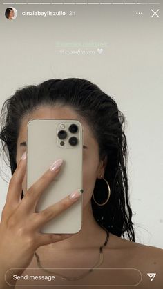 a woman taking a selfie with her cell phone in front of her face and wearing gold hoop earrings