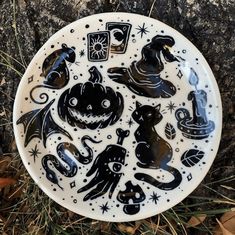 a black and white plate sitting on top of the ground next to some dry grass