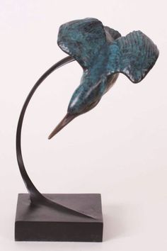 a bronze sculpture of a bird on a black stand