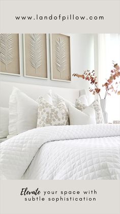 a bed with white sheets and pillows in front of two framed pictures on the wall