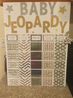 a baby jeo party sign on top of a counter with gold and silver glitters