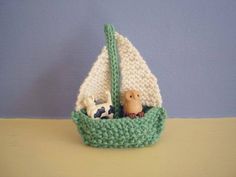 a knitted toy sailboat with animals in it