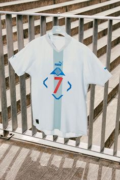 a white shirt hanging on a fence with the number seven printed in blue and red