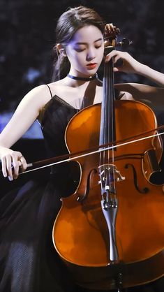 a woman in a black dress is playing the cello