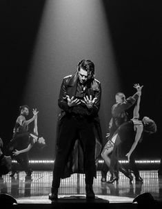 a man standing on top of a stage in front of dancers