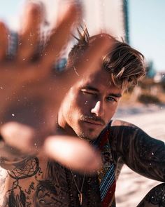 a man with tattoos sitting on the beach