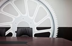 a conference room with a large white wheel on the wall and black chairs in front of it