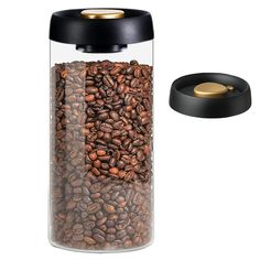 a glass jar filled with coffee beans next to a black lid