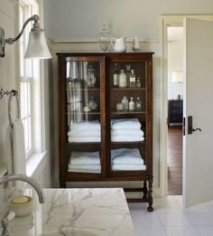 a bathroom with marble counter tops and white linens on display in the glass cabinet