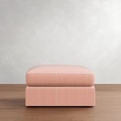 an upholstered footstool sitting on top of a wooden floor next to a wall